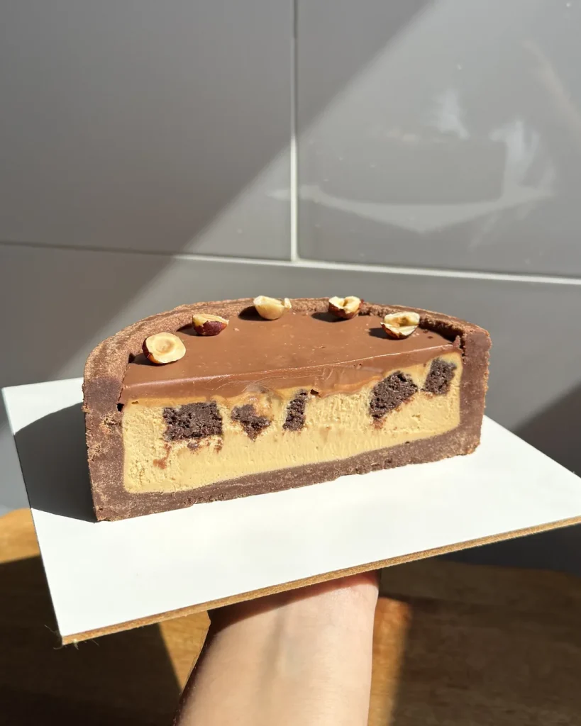 Corte del cheesecake de dulce de leche y brownie con avellanas
